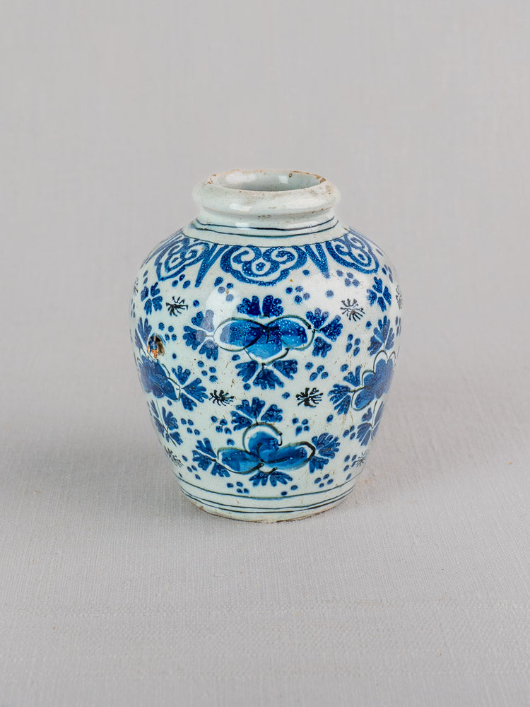 Antique Dutch Delft blue and white faience vase with intricate floral designs and short neck on gray background.