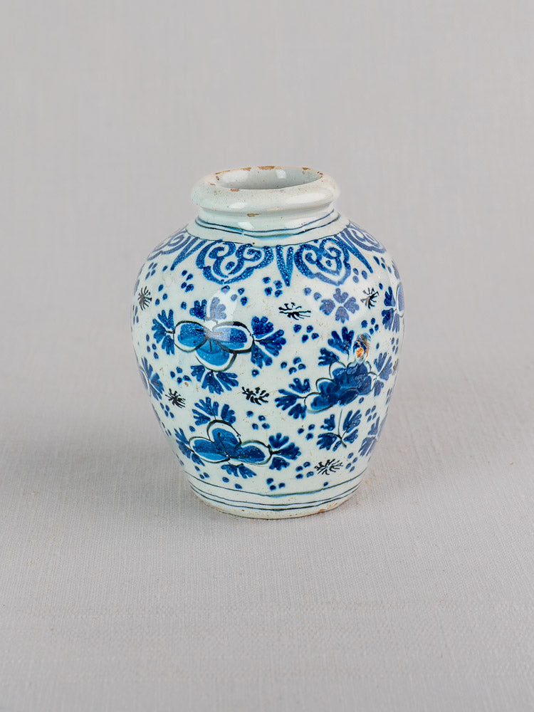 18th century Dutch Delft vase in blue and white faience with intricate chinoiserie floral motifs on light grey background.