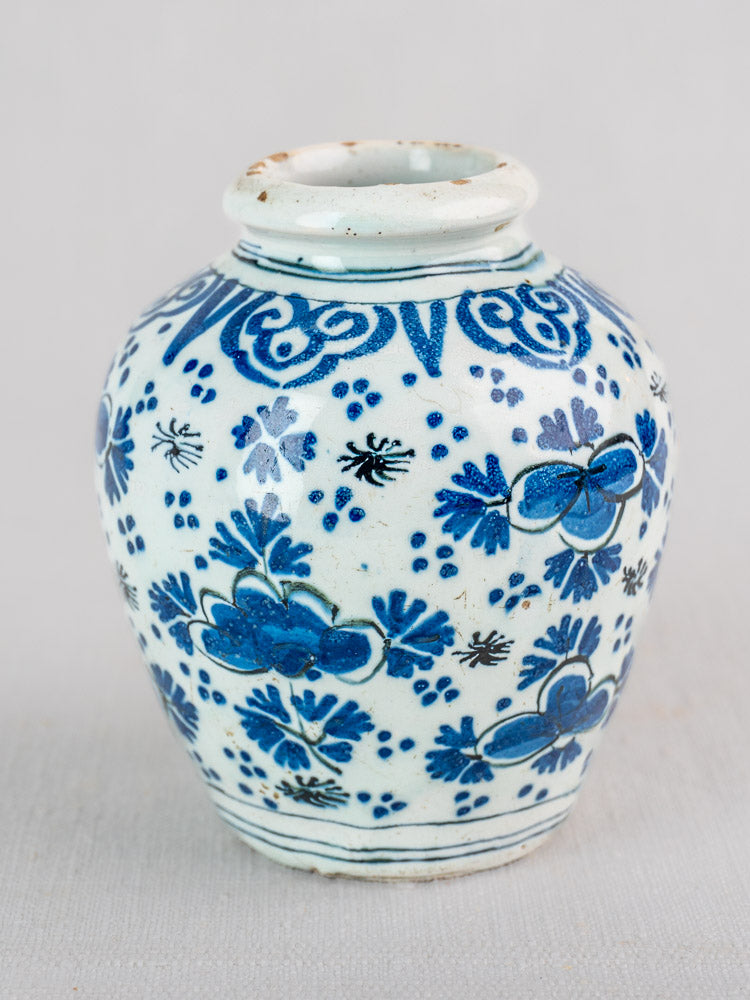 Small round white ceramic Dutch Delft vase with blue floral patterns, flared neck, glossy finish, 18th-century faience.