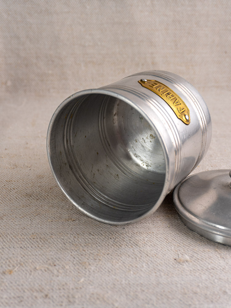 Mid-century French aluminum canister with lid and brass “FARINE” label, shown on a textured beige surface.