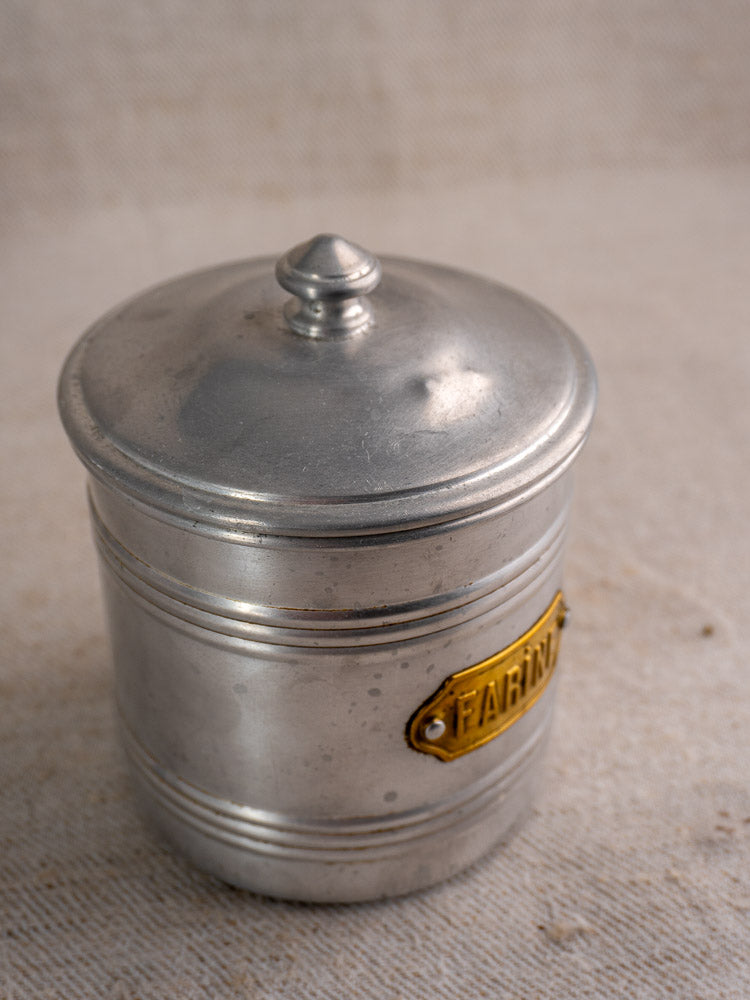Vintage French aluminum canister with brass FARINA label and lid from a mid-20th century kitchen set.