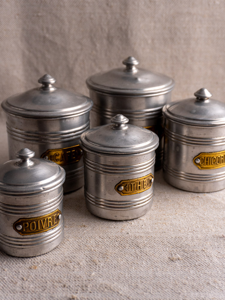 Vintage French aluminum canister set with brass labels, five lidded pieces marked Poivre, Café, Thé, Chicorée.