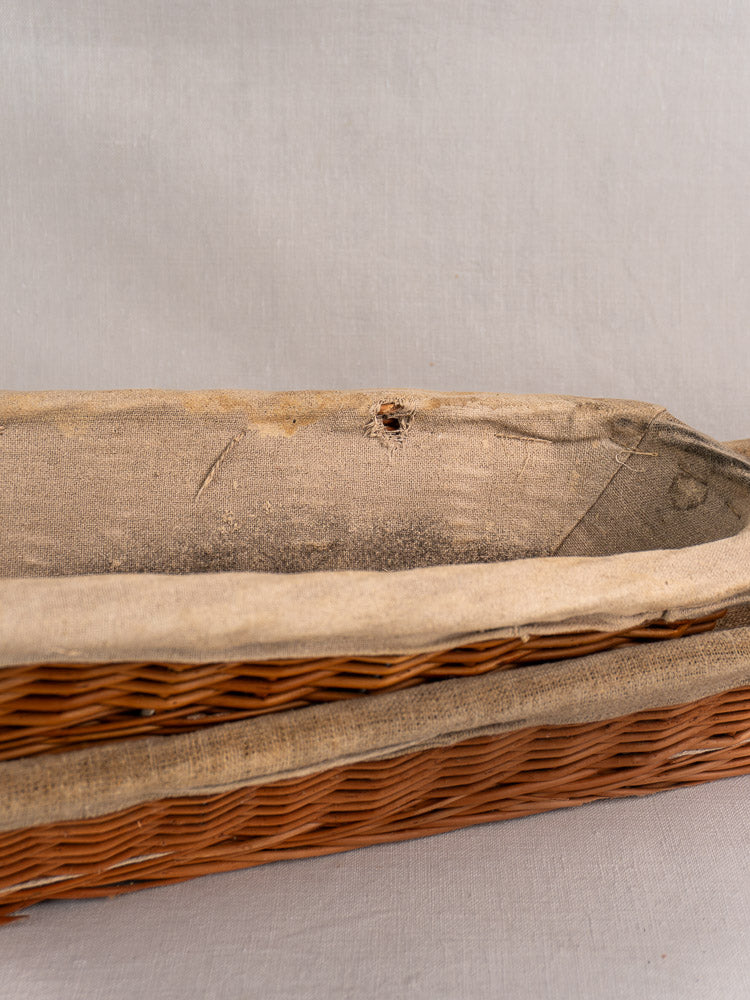 Vintage French baguette proofing basket, circa 1940-1950, with worn linen liner showing a small hole and visible stitching.