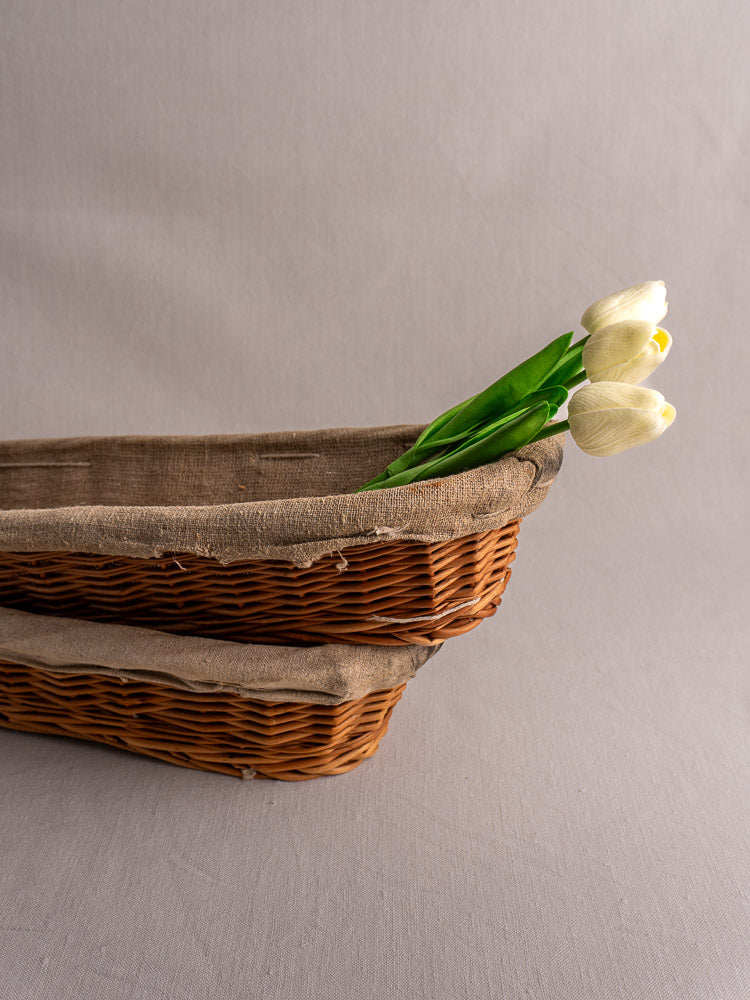Pair of vintage French baguette proofing baskets, circa 1940-1950, linen-lined, stacked on light gray surface.