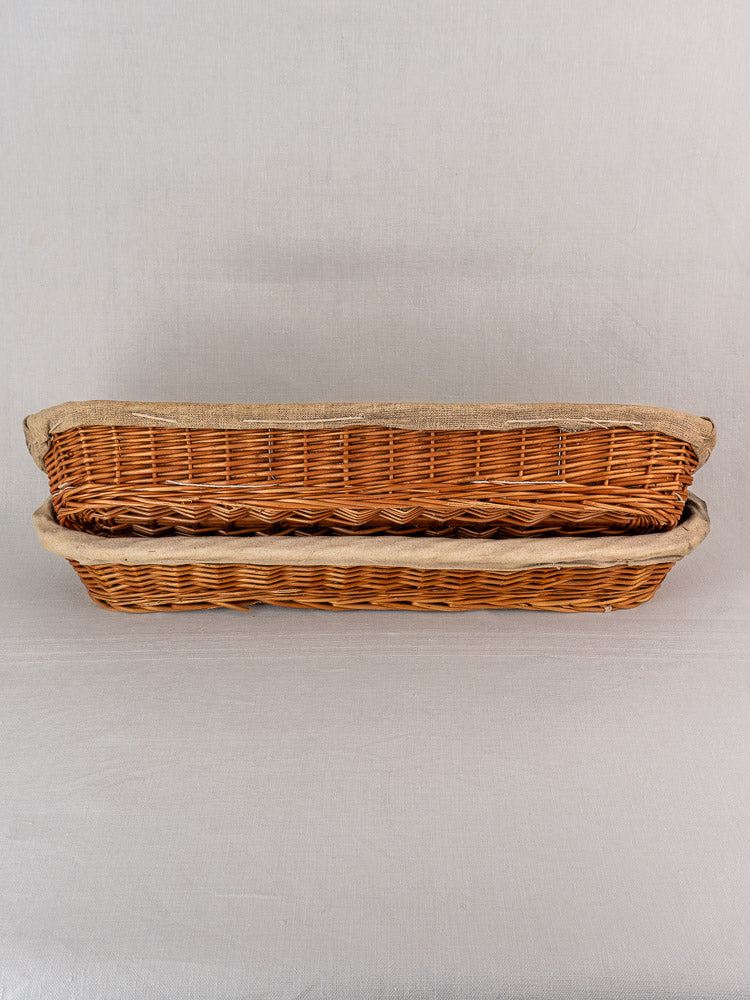Pair of vintage French baguette proofing baskets with linen liners, circa 1940-1950, stacked on a light background.
