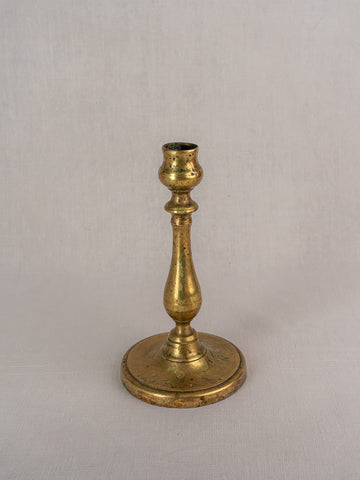 Antique French brass candlestick, 19th century, with turned baluster stem and round base on neutral background.