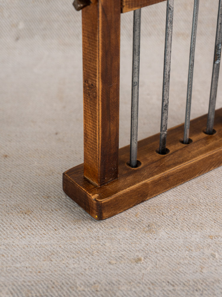 Vintage French brochette skewers with brass animal finials in a wooden stand on beige fabric.