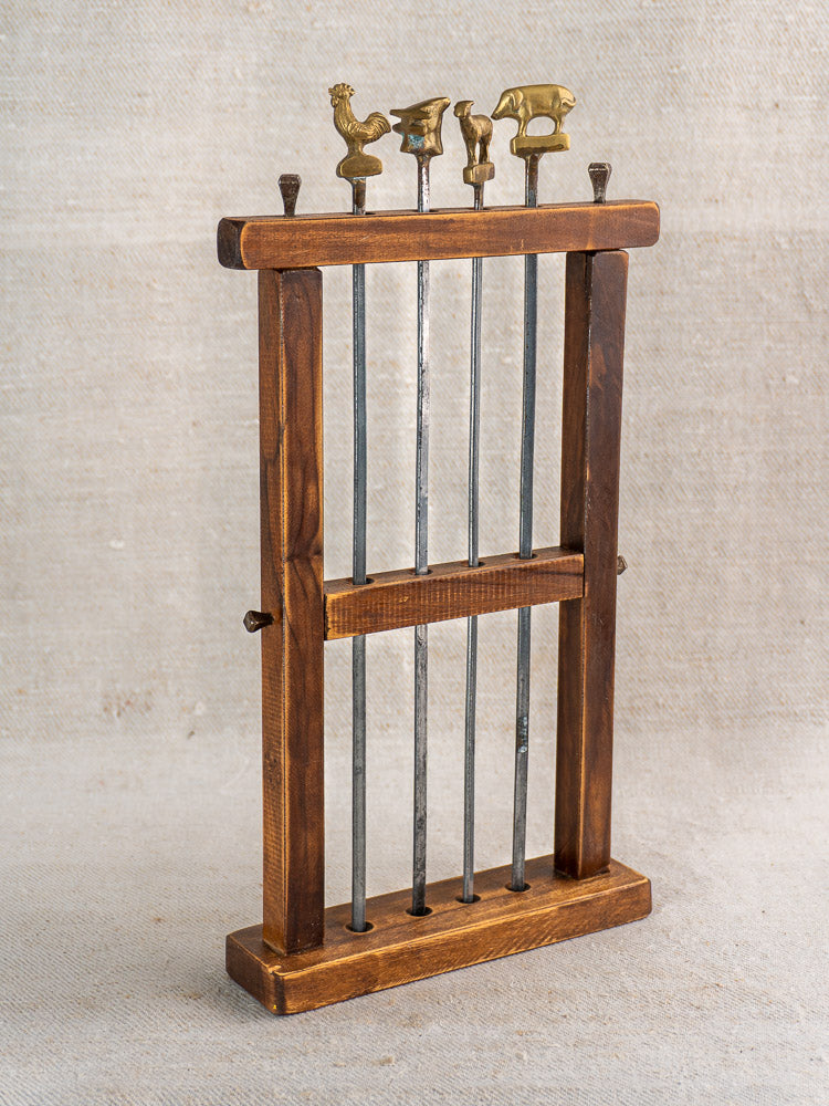 Set of four vintage French metal brochette skewers with brass animal finials in wooden stand on burlap.