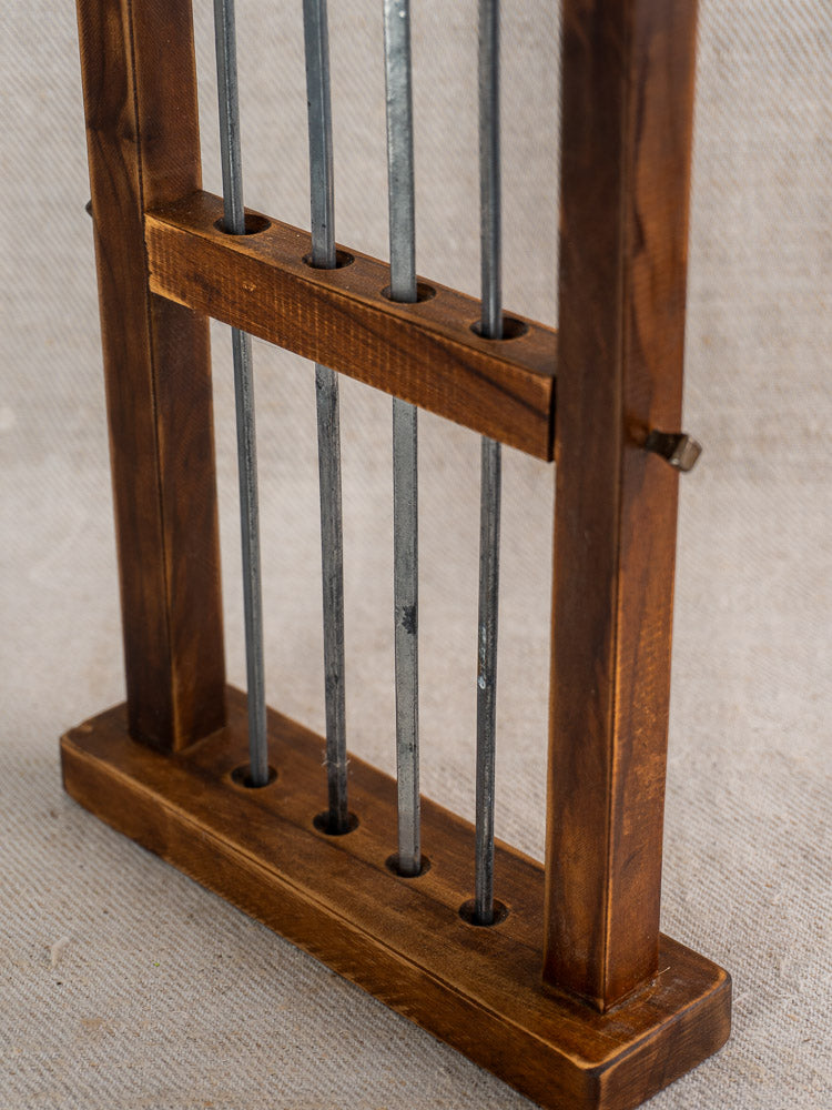 Vintage French brochette skewers set with brass animal finials on wooden stand, textured fabric backdrop.