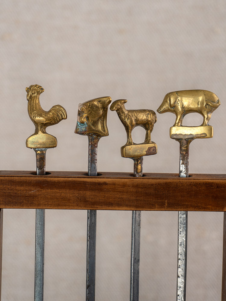 Vintage French brochette skewers set with brass animal finials in a wooden stand.