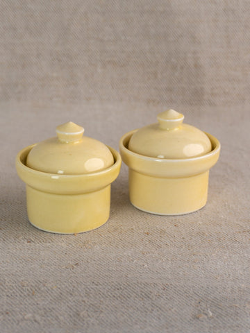 Pair of vintage French cream-glazed butter pots from the mid-20th century on neutral textured fabric.