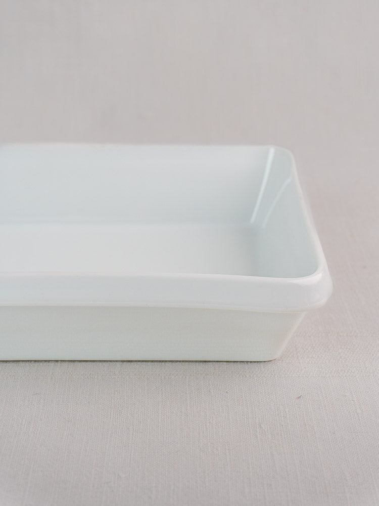 White vintage French porcelain baking dish with smooth edges on a light surface, classic bakeware style.