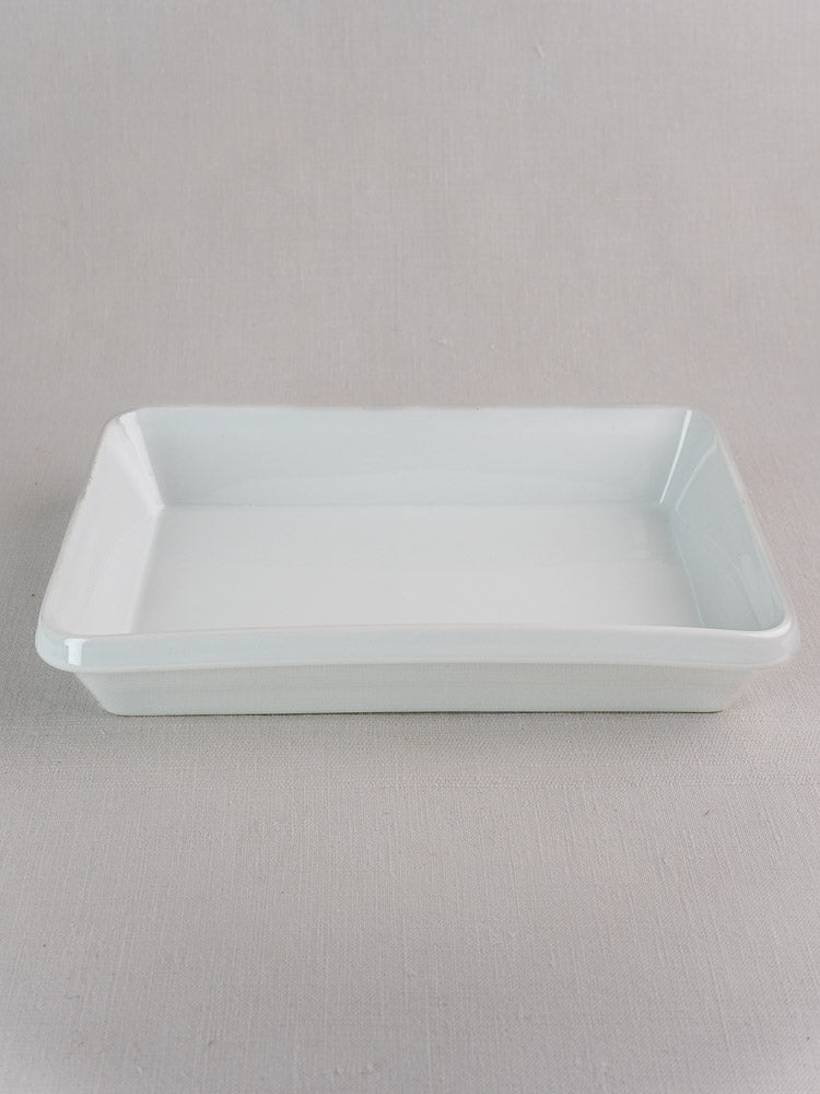 Vintage French white porcelain rectangular baking dish on a light, textured surface with neutral background.