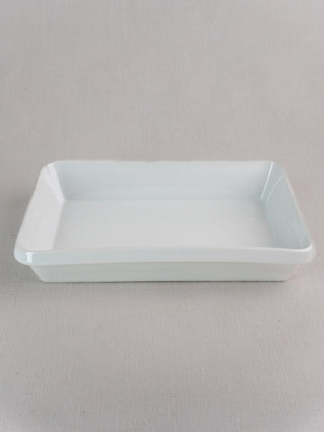 Vintage French white porcelain rectangular baking dish on a light, textured surface with neutral background.