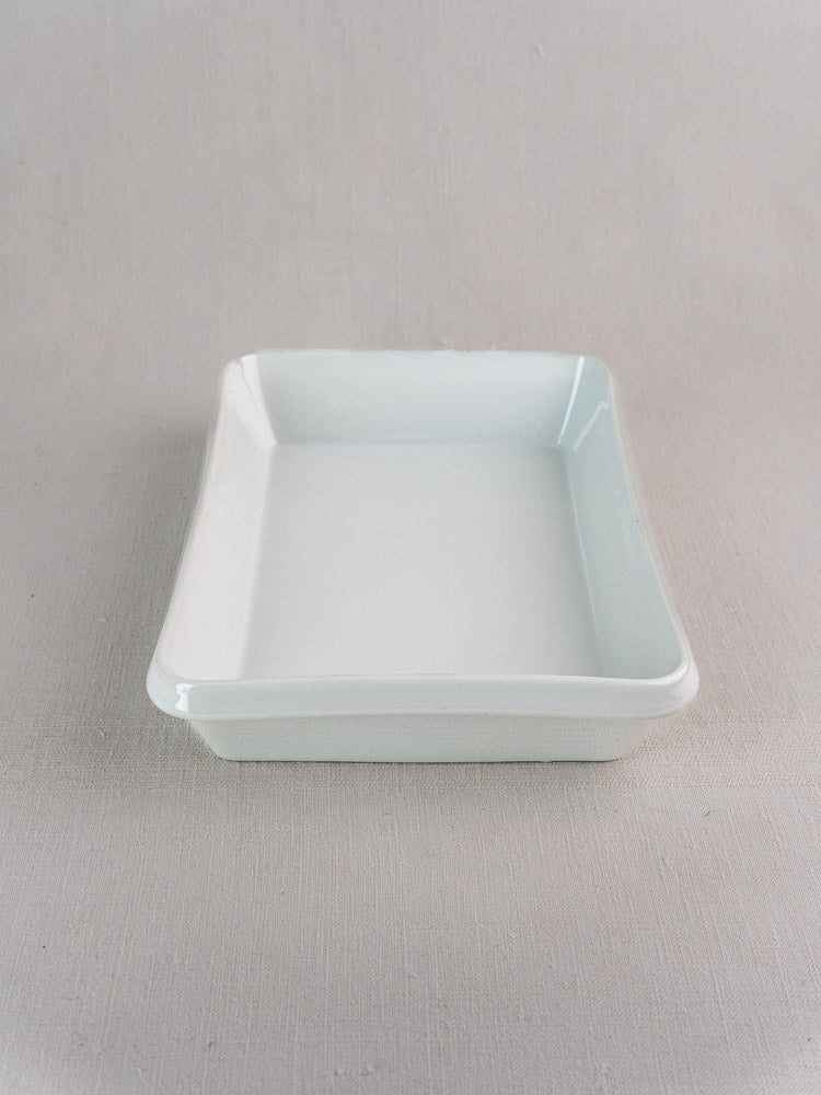 Vintage French porcelain baking dish, white rectangular plat à four on a light textured surface.