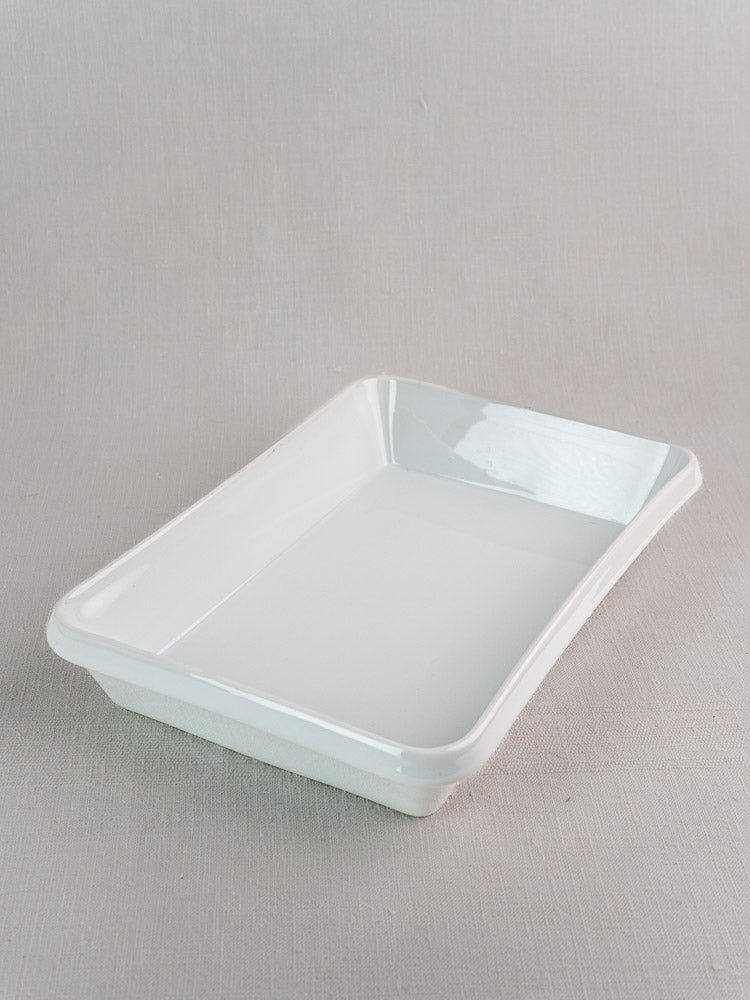 Vintage French porcelain baking dish, white rectangular plat à four on a textured grey background.