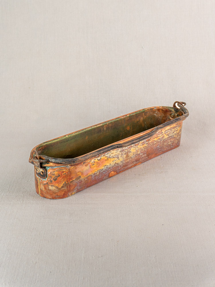 19th-century French copper poissonniere fish kettle with twin handles and patina, on neutral fabric background.