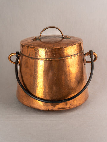 Antique French copper lidded cauldron with side rings and black handle on a neutral background.