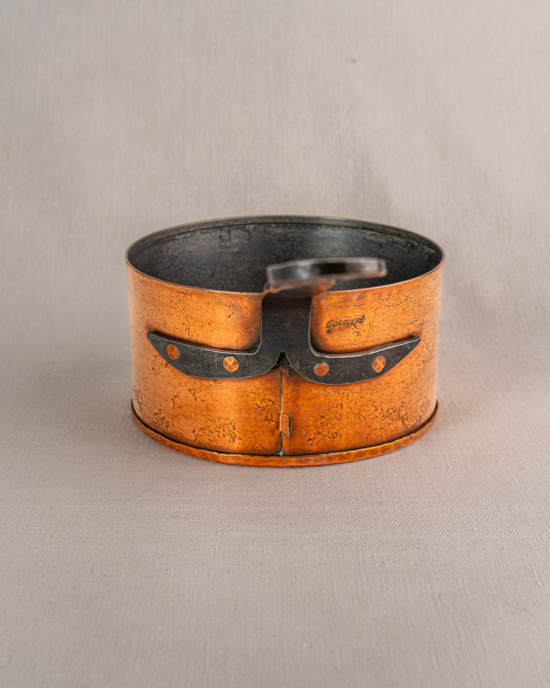 Set of four vintage Jean Goardère French copper saucepans with dark interiors and riveted handles on a neutral background.