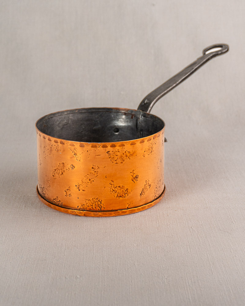 Set of four vintage Jean Goardère copper saucepans with long metal handles on light gray background.