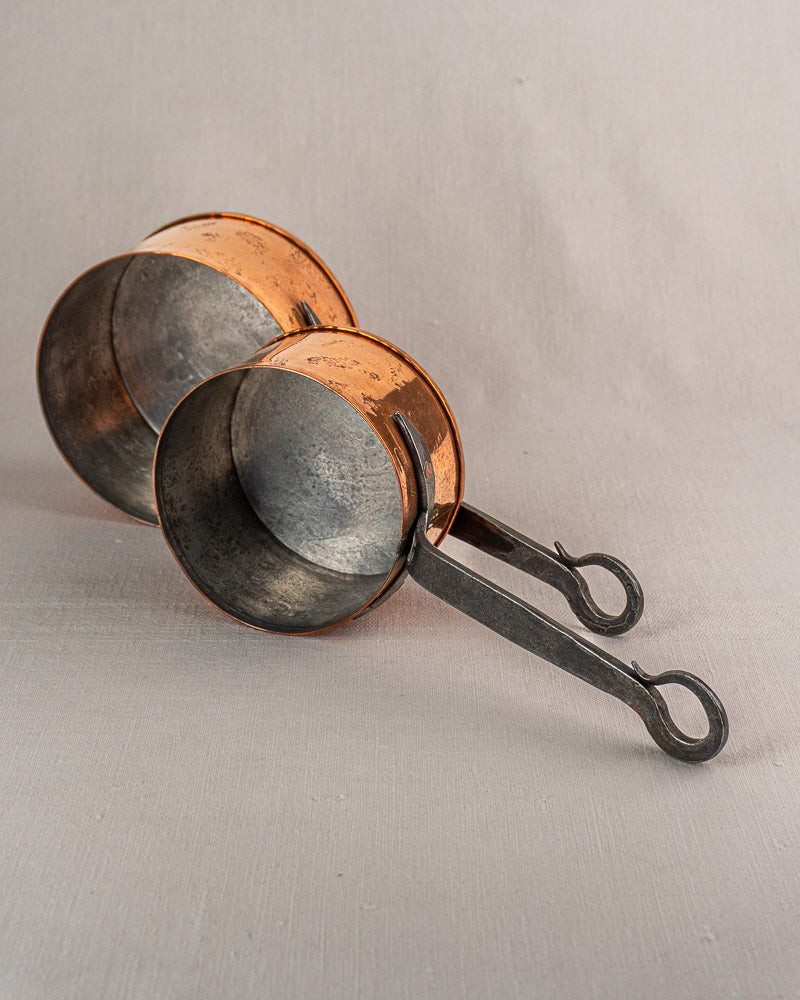 Set of four vintage French copper saucepans with polished exteriors, displayed on light gray fabric.