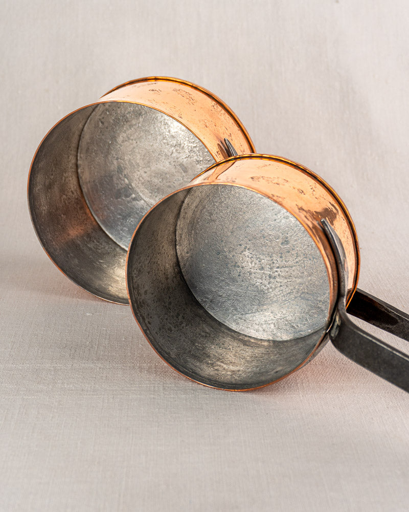 Set of four vintage French copper saucepans by Jean Goardère with silver-toned interiors on light textured surface.