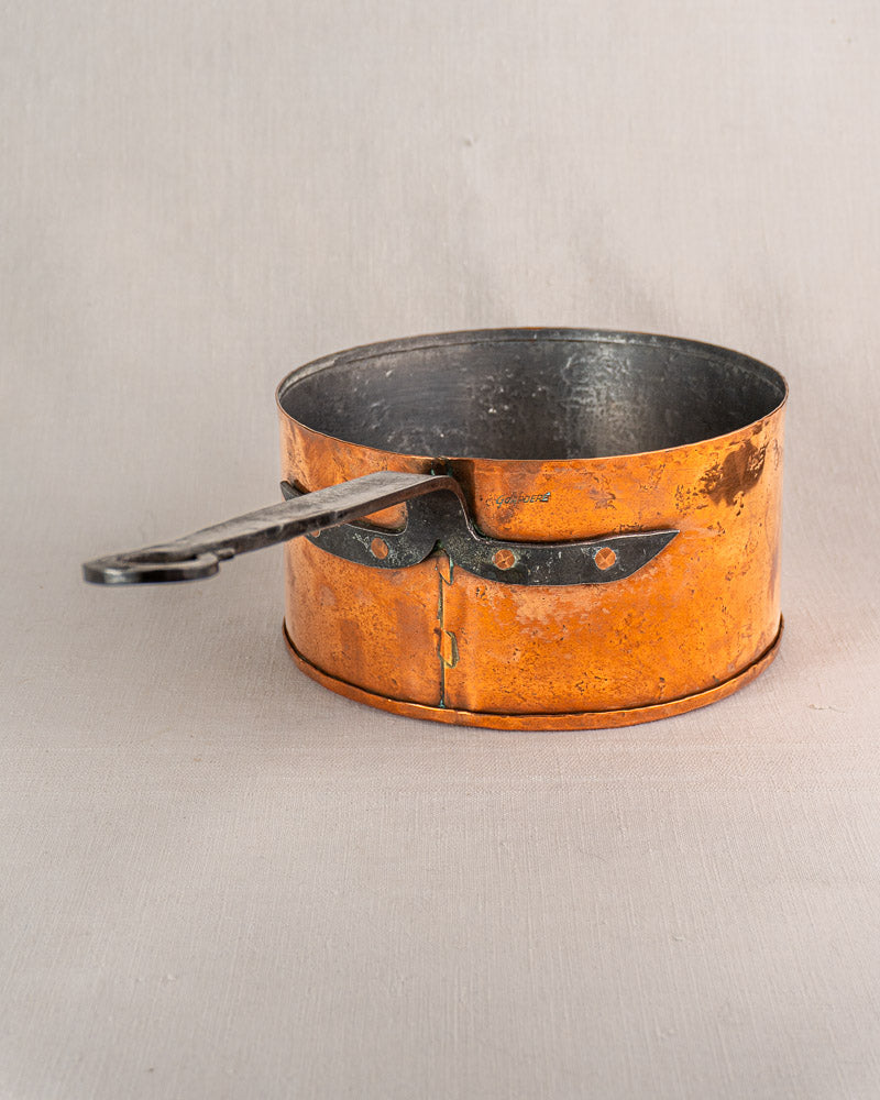 Set of four vintage French copper saucepans by Jean Goardère with metal handles and patina on light gray surface.