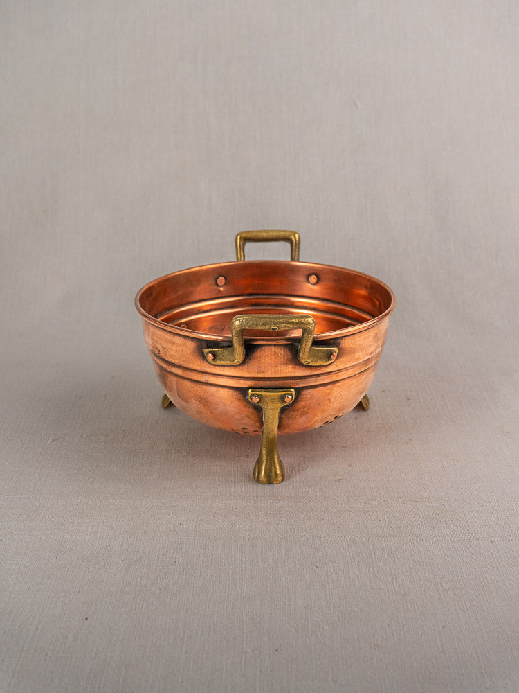 Antique French copper colander with brass paw feet, early 20th century, nested kitchen bowl, neutral fabric.