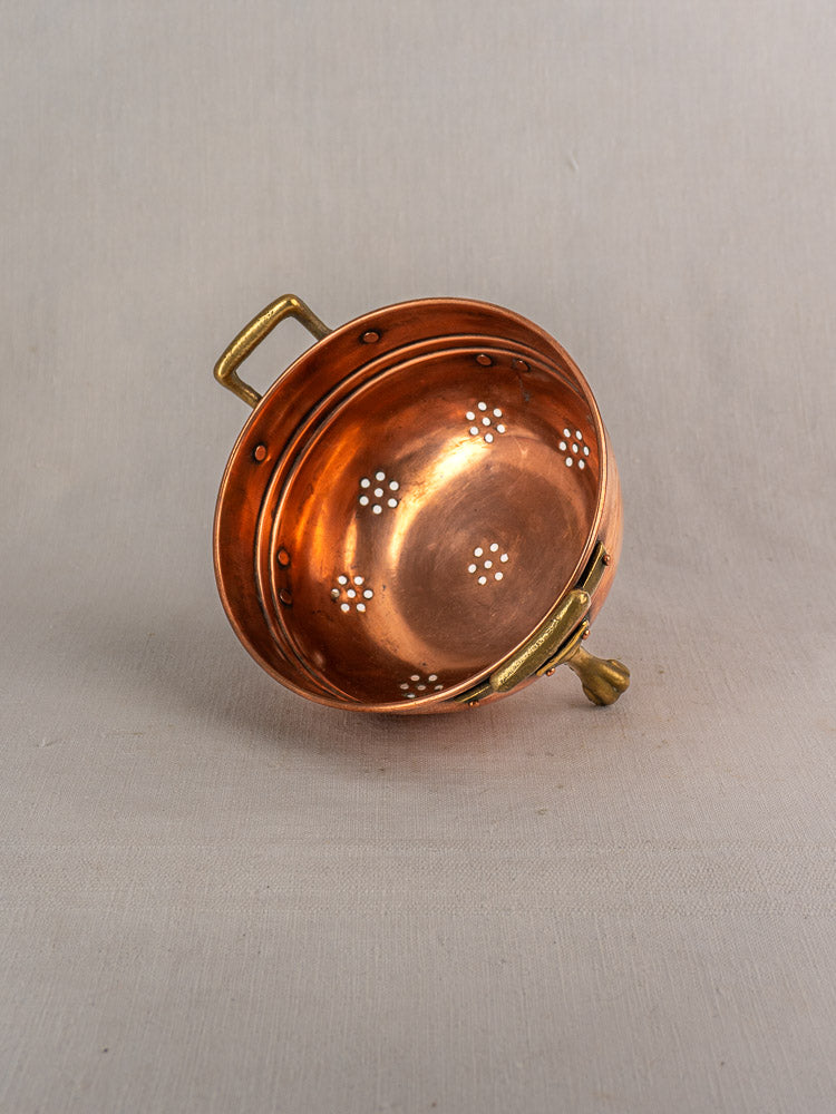 Antique French copper colander set of three with brass paw feet, decorative perforations, on a light textured surface.