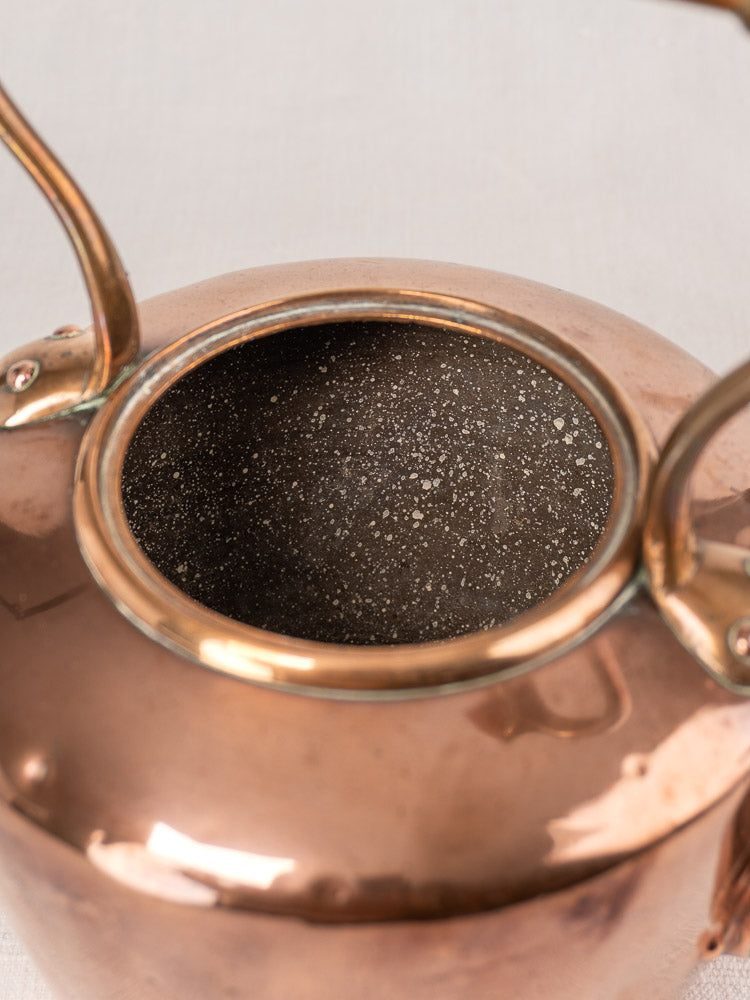 Antique French copper tea kettle, late 19th century, with polished exterior, wood handle, and speckled dark interior.