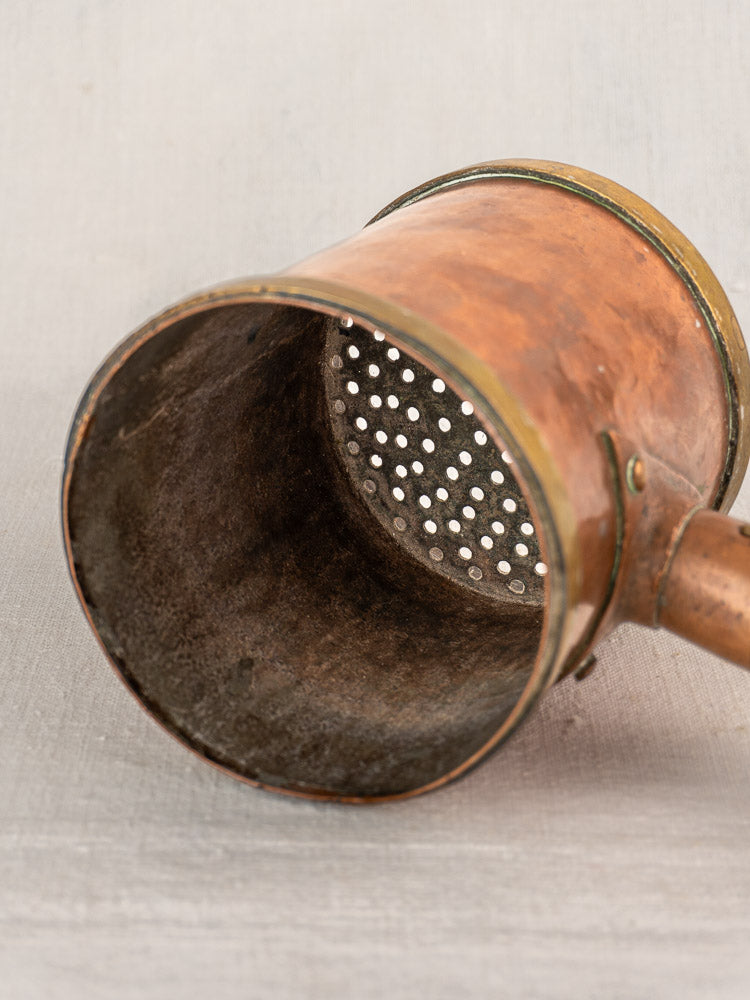 Antique French copper strainer pot by L. Fraiche Carcassonne with perforated mesh and wooden handle on light surface.