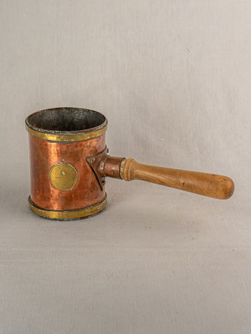 Antique French copper strainer pot by L. Fraiche Carcassonne, cylindrical with wooden handle, on neutral fabric background.