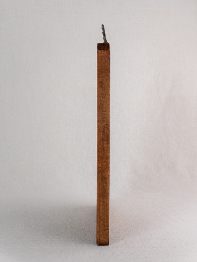 Antique French cutting board circa 1890–1920 with hand-forged iron handle, upright on a light background.