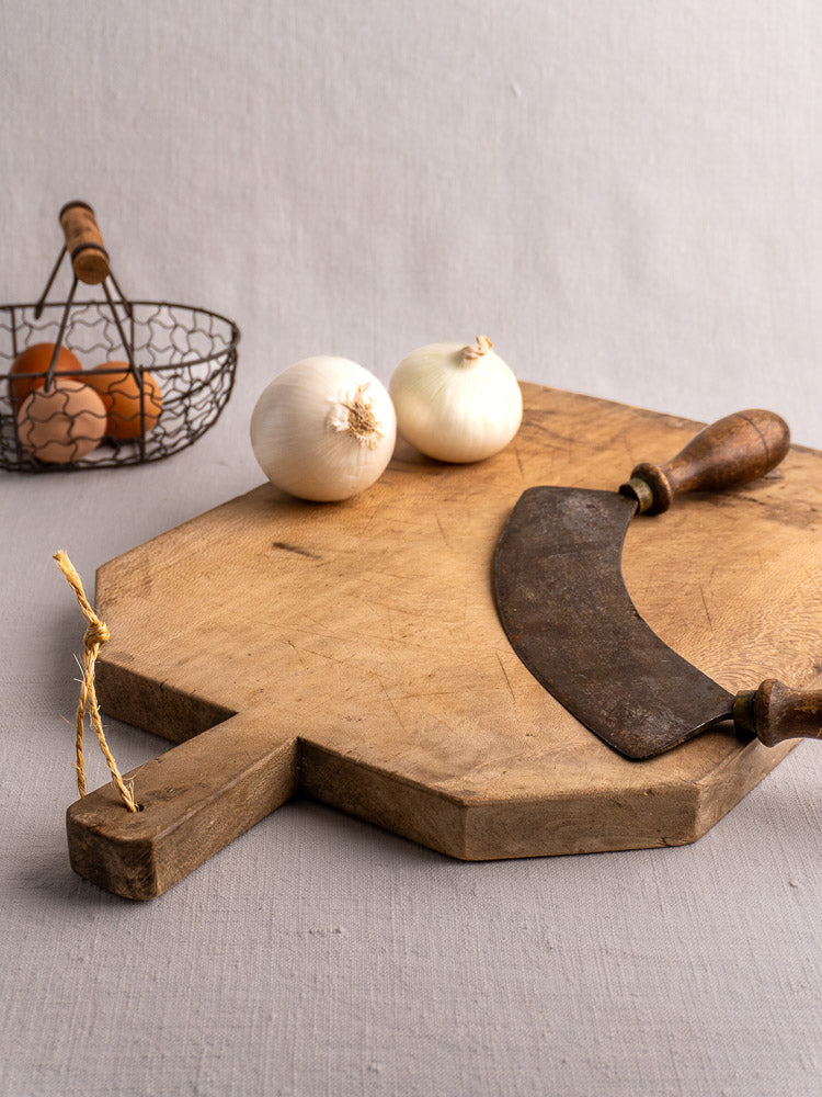 Hand carved antique French bread board with handle and yellow string, shown upright on a light gray background.