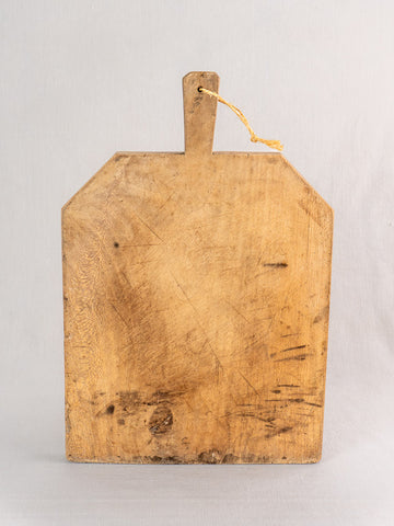 Hand carved antique French bread board with handle and yellow string, shown upright on a light gray background.