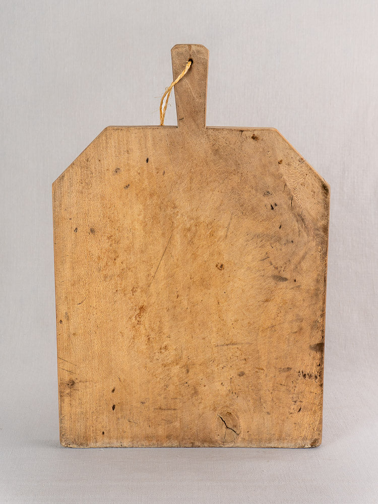 Antique French beech bread board, hand-carved in provincial farmhouse style, displayed upright on light grey background.