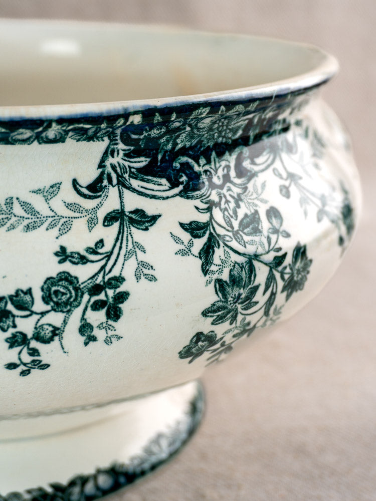 Antique French Saint-Amand faience soupière with black fruit and floral pattern, neutral blurred background.