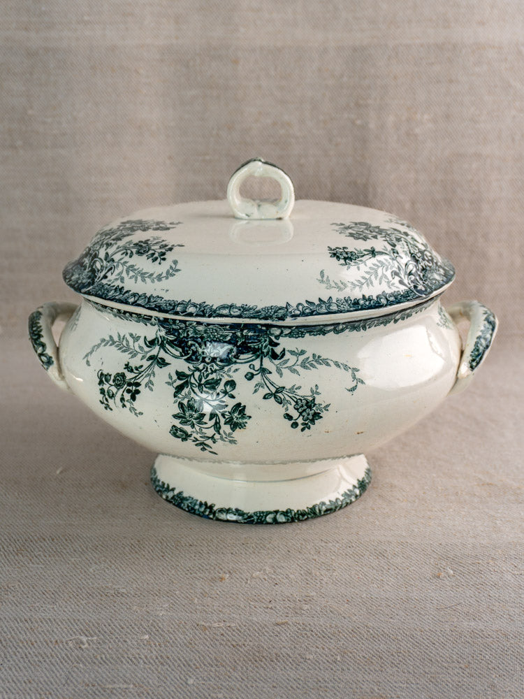 Antique French Saint-Amand white faience soupière with lid, green fruits pattern, on neutral fabric.