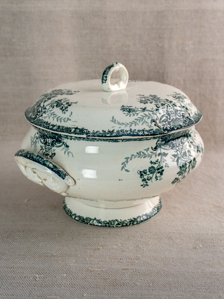 Antique French Saint-Amand faience soupière with fruit pattern, lid, and side handles on beige fabric.