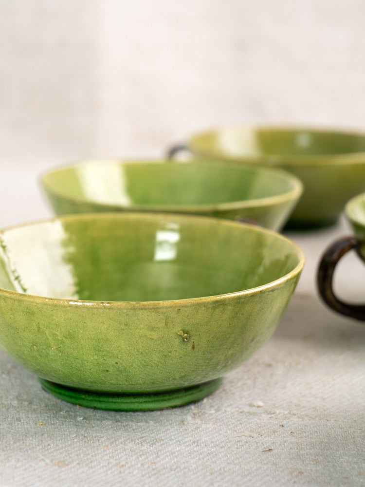Set of six vintage French teacups with Dieulefit green glaze arranged on a neutral textured surface.