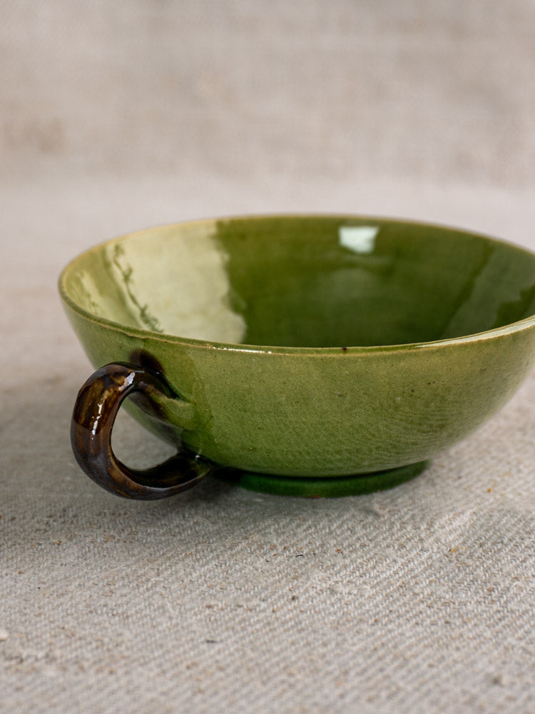 Set of six vintage French teacups with Dieulefit green glaze and dark brown curved handles on beige textured surface.