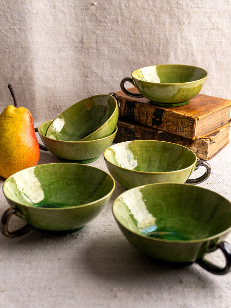 Set of six vintage French teacups in Dieulefit green glaze, displayed on textured linen fabric.