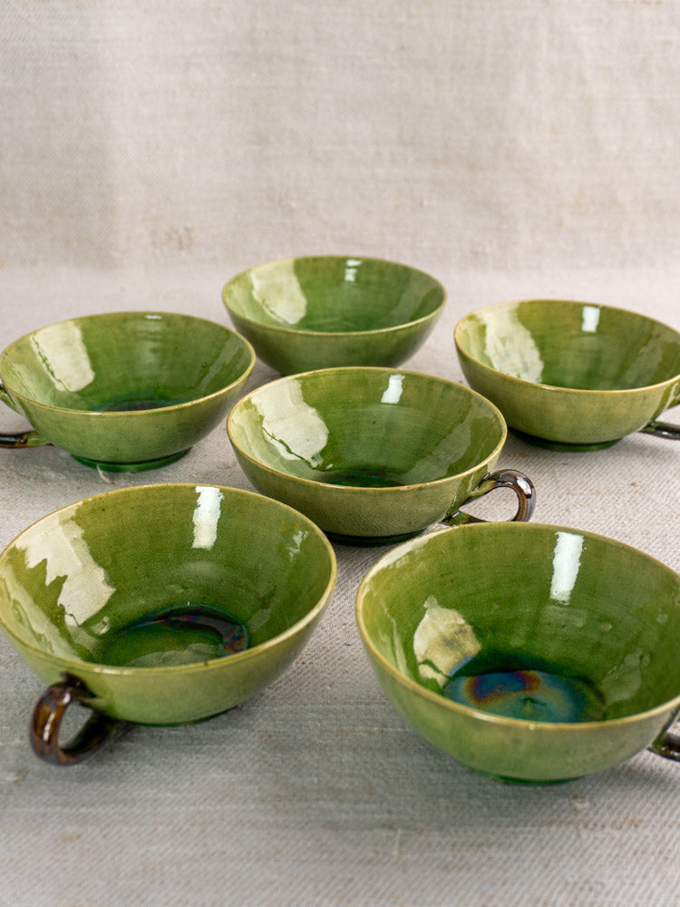 Set of six vintage French teacups in Dieulefit green glaze, displayed on textured linen fabric.