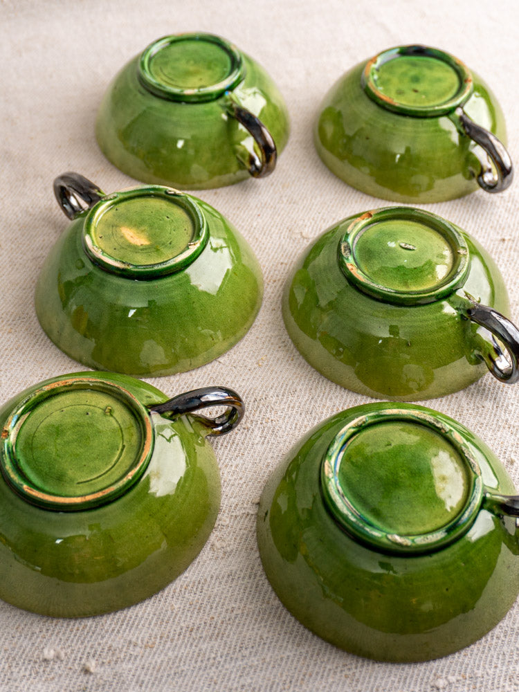 Set of six vintage French teacups with Dieulefit green glaze, upside down to display glossy bases and natural color variations.