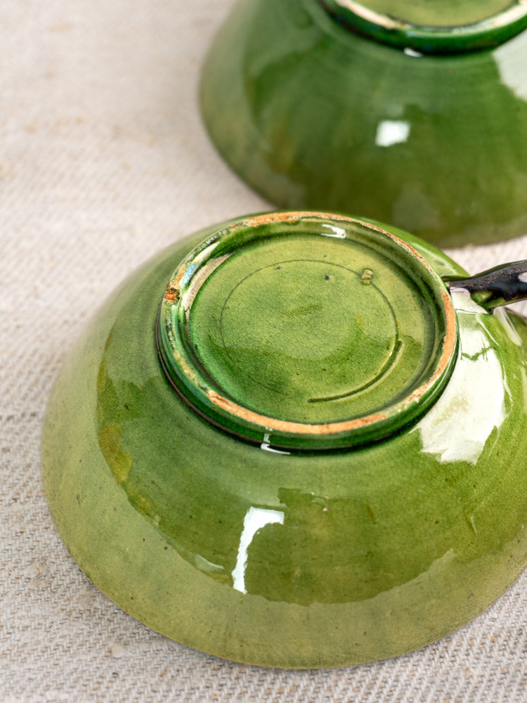 Six vintage French teacups in Dieulefit green glaze, upside down to reveal unglazed bases and circular patterns.