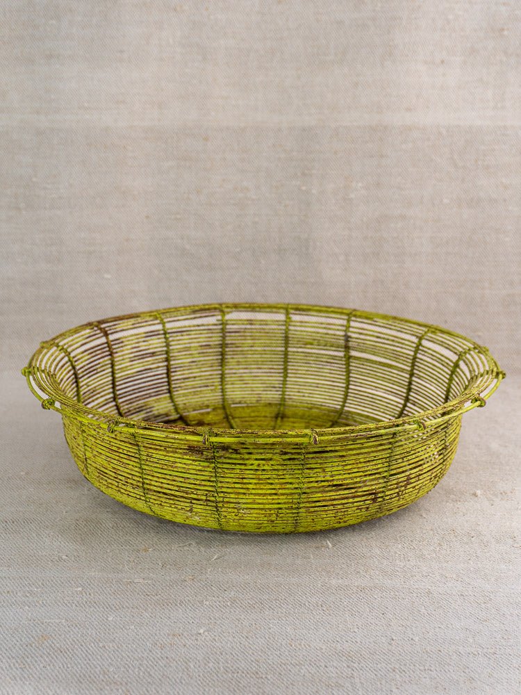 Antique French wire basket, circa 1900, round and shallow with rustic green paint on fabric background.