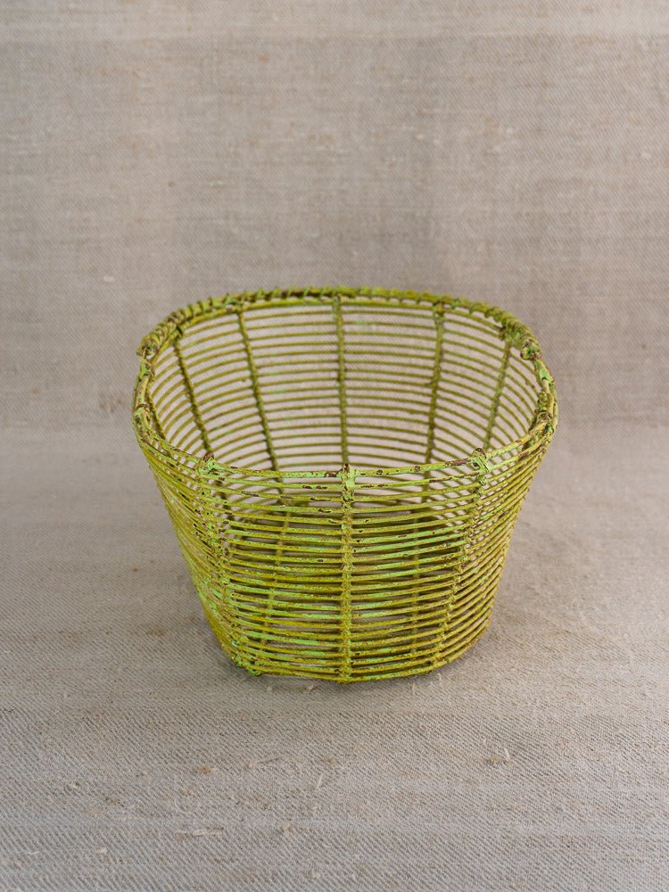 Antique French wire basket, circa 1900, painted vintage green with open weave, on beige fabric.