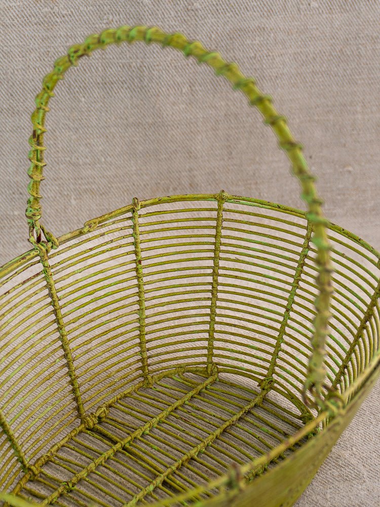 Antique French wire basket set with green painted fil de fer, circa 1900, on beige textured fabric.