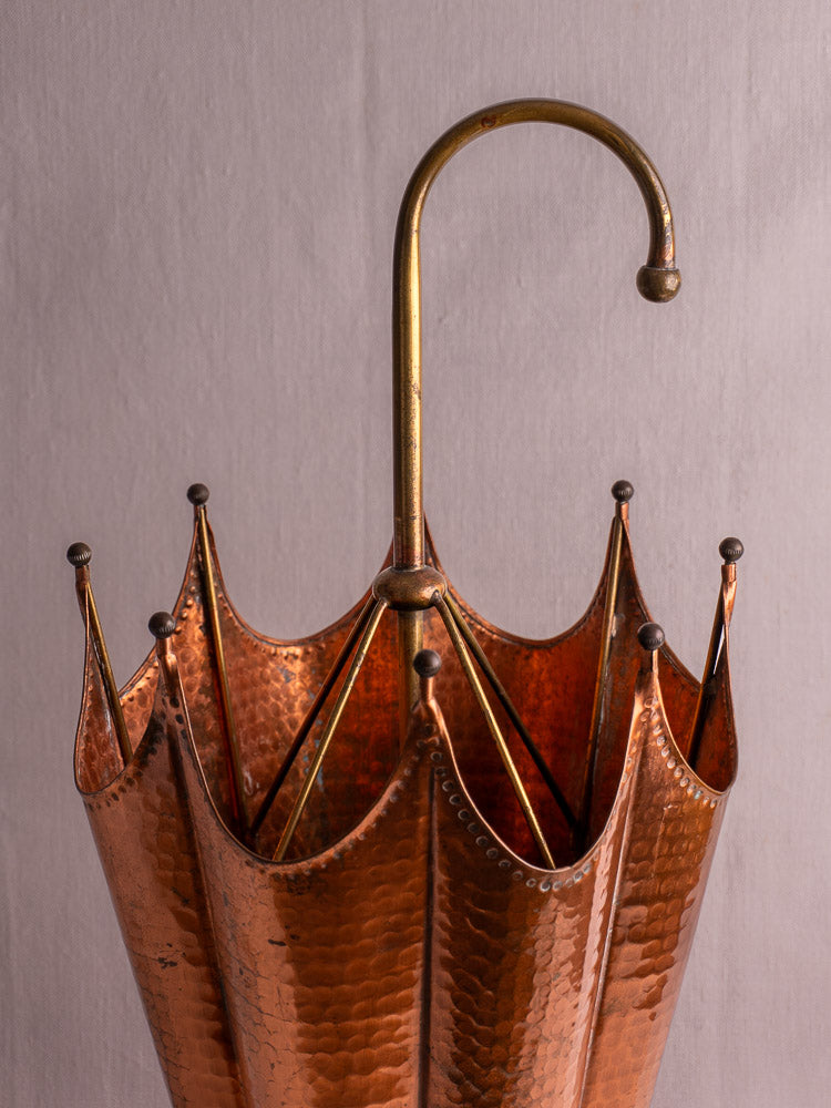 Mid-century French hammered copper umbrella stand with brass handle, umbrella-shaped, on light gray background.