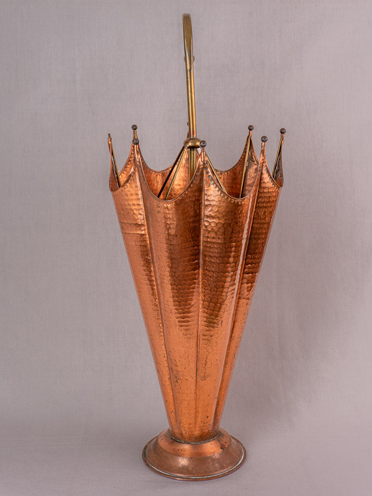 Mid-century French hammered copper umbrella stand with brass handle and finials, on light gray background.